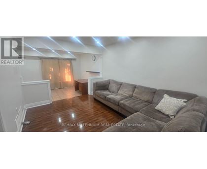 A living room with a grey couch and wooden floors.