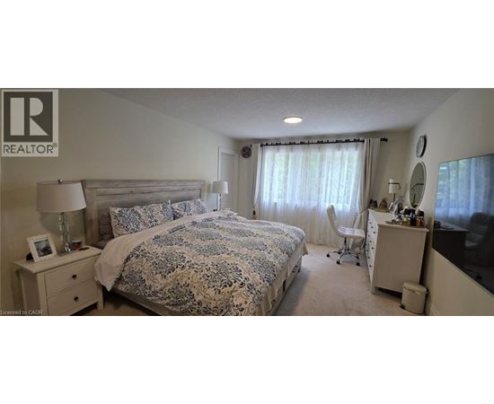 A bedroom with a large bed and a desk with a chair.