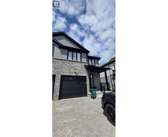 A modern house with a black garage door and a green trash bin.