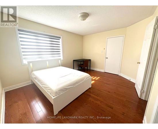 A bedroom with a bed, desk, and window.