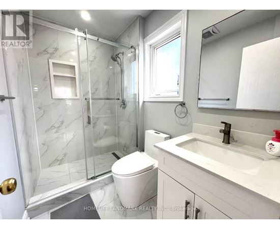 A bathroom with a marble shower and white toilet.