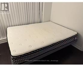 A white mattress with a black patterned border is displayed in a room.