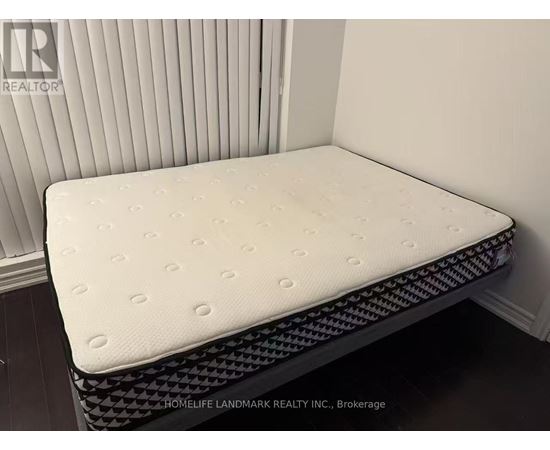 A white mattress with a black patterned border is displayed in a room.
