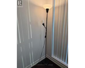 A floor lamp with a white shade stands in a corner of a room.