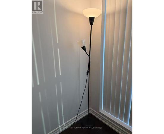 A floor lamp with a white shade stands in a corner of a room.