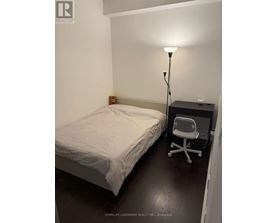 A bedroom with a bed, chair, and lamp.
