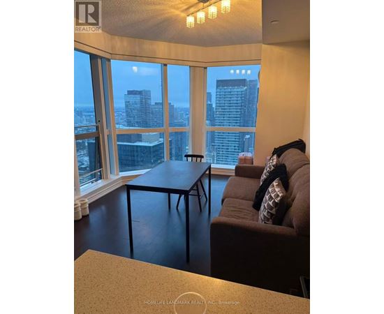 A living room with a couch and a table in front of a large window with a city view.