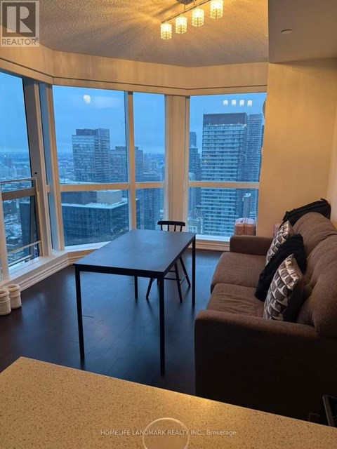 A living room with a couch and a table in front of a large window with a city view.