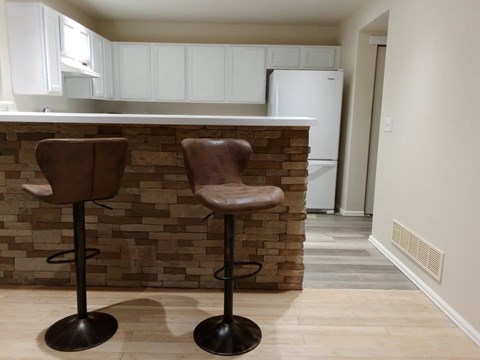Two brown bar stools in front of a brick wall.