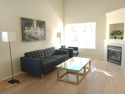 A living room with a black couch and a glass coffee table.