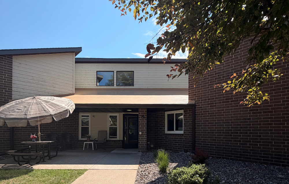 A house with a patio and a tree branch in the foreground.