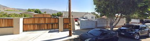 A black car is parked in front of a wooden fence.