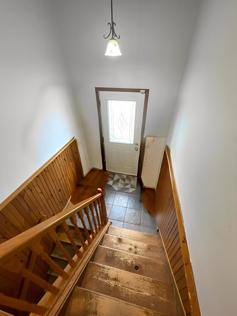 A wooden staircase with a light hanging from the ceiling.