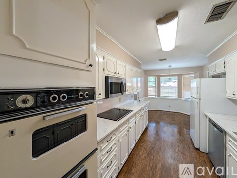 A kitchen with white cabinets and a black stove top oven.