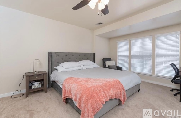 A bedroom with a bed, a chair, and a ceiling fan.