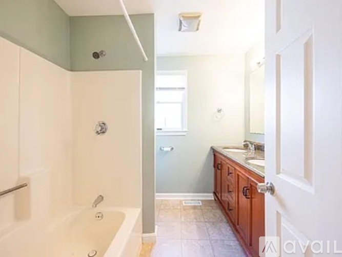 A bathroom with a tub, sink, and mirror.