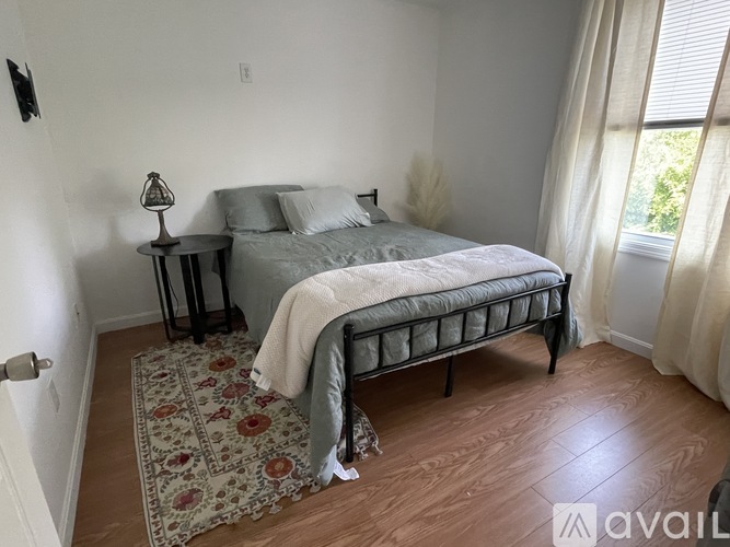 A bedroom with a bed, nightstand, and rug.
