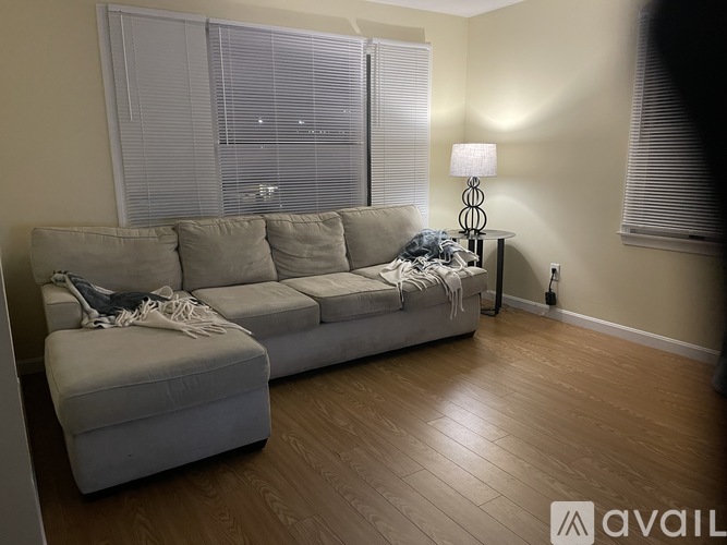 A living room with a grey couch and a lamp on a side table.
