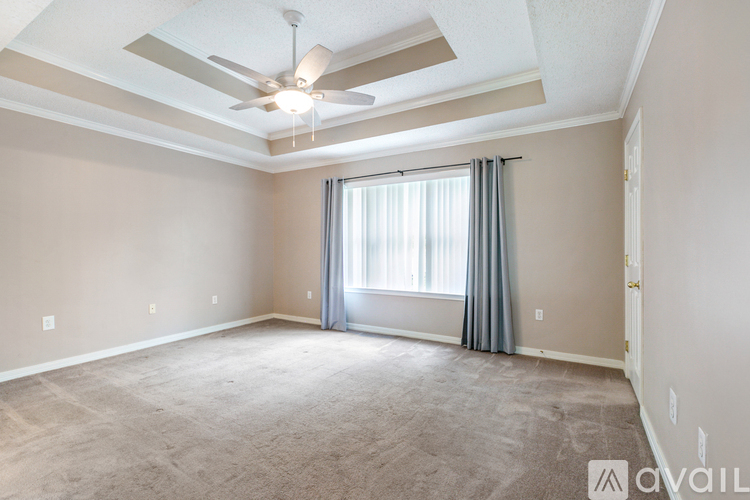 A spacious room with a ceiling fan and carpeted floor.