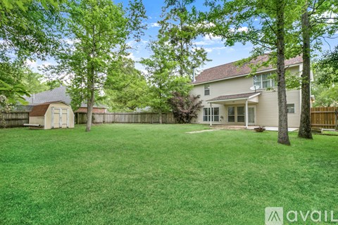A backyard with a house, a tree, and a fence.