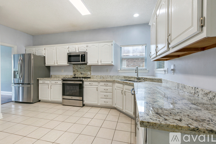 A kitchen with white cabinets and granite countertops.