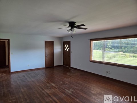 A room with a ceiling fan and wooden floors.
