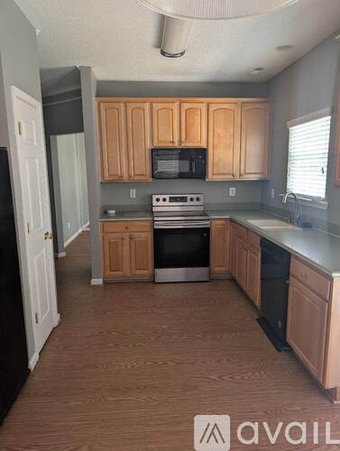A kitchen with wooden cabinets and a black refrigerator.