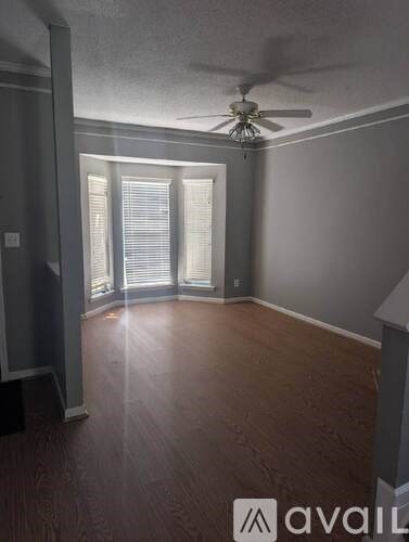 A room with a ceiling fan and sliding glass doors.