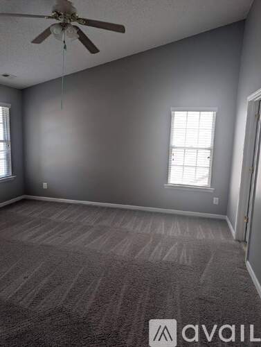 A room with a ceiling fan and carpeted floor.