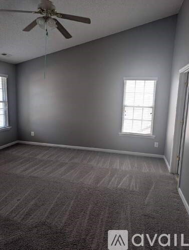 A room with a ceiling fan and carpeted floor.