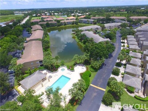 A bird's eye view of a residential area with a swimming pool and a lake.