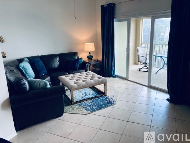 A living room with a black couch and a small ottoman.