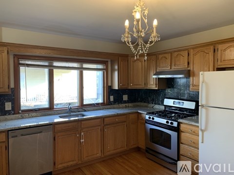A kitchen with wooden cabinets and a chandelier.