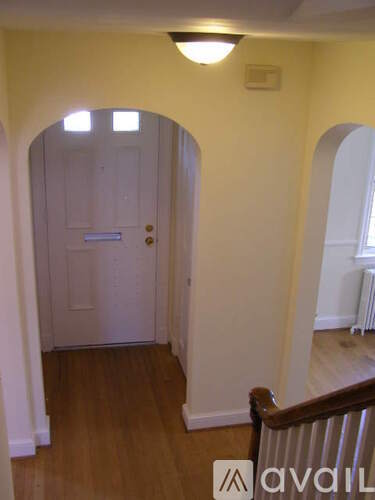 A hallway with a white door and wooden floors.