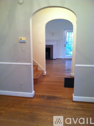 A hallway with a white archway leading to a door.