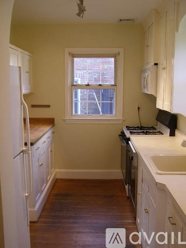 A kitchen with white cabinets and a window overlooking a city street.