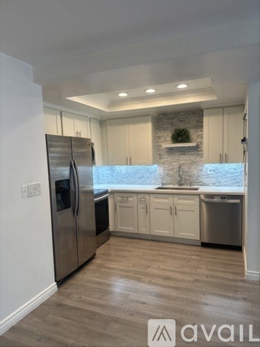A kitchen with a stainless steel refrigerator and wooden flooring.