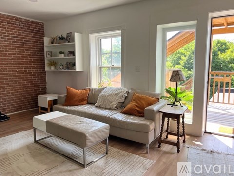 A living room with a white couch and a brick wall.
