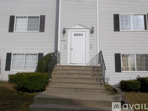 A two-story house with a white door and black shutters.