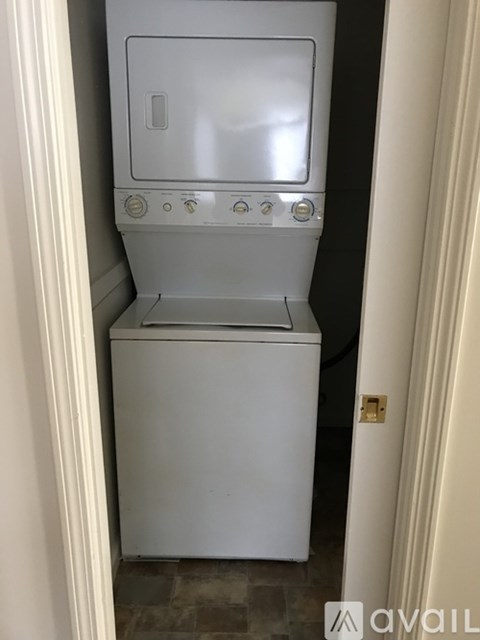 A white dishwasher and dryer stacked on top of each other in a narrow space.