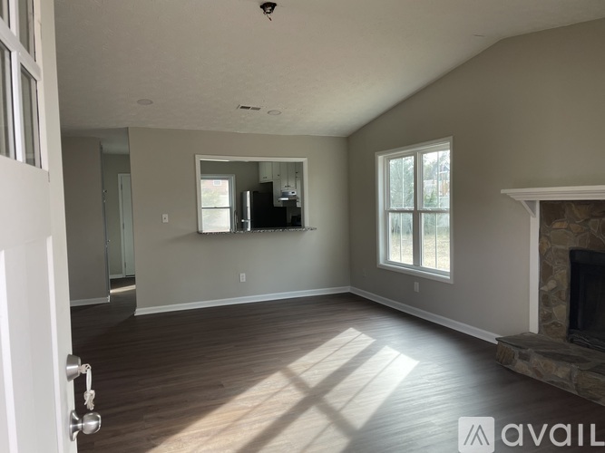 A spacious living room with wood flooring and a fireplace.