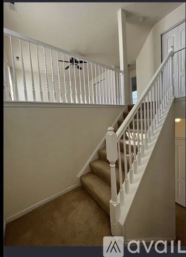 A staircase with a white railing and beige carpeting.