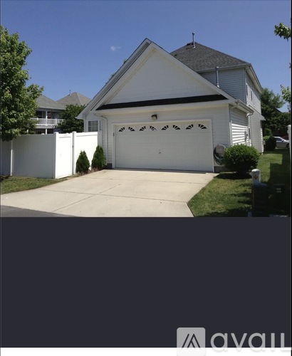 A white house with a black roof and a white garage door.