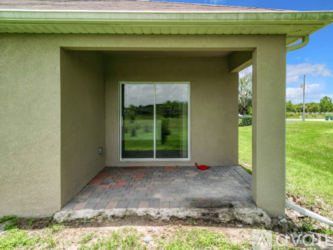 A small house with a glass door and a brick walkway leading to it.