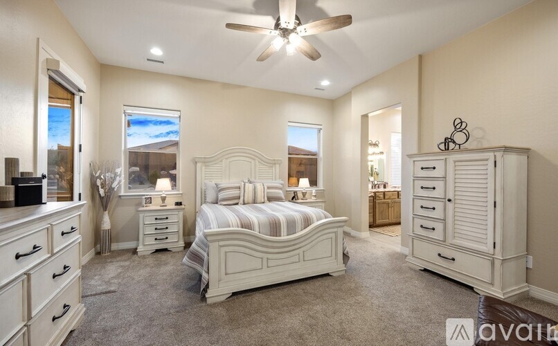 A bedroom with a large bed, dresser, and a ceiling fan.