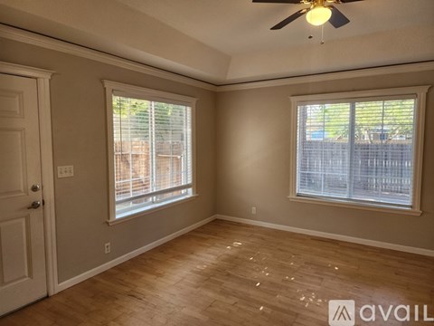A room with a ceiling fan and two windows.