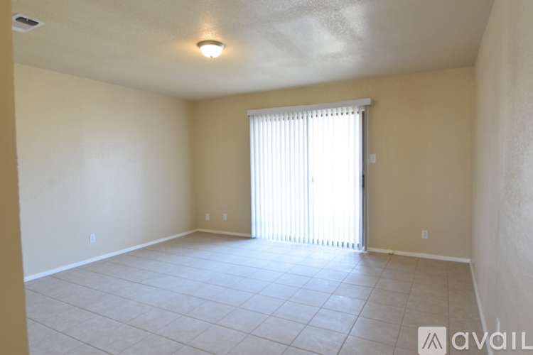 A spacious room with a window covered by blinds.