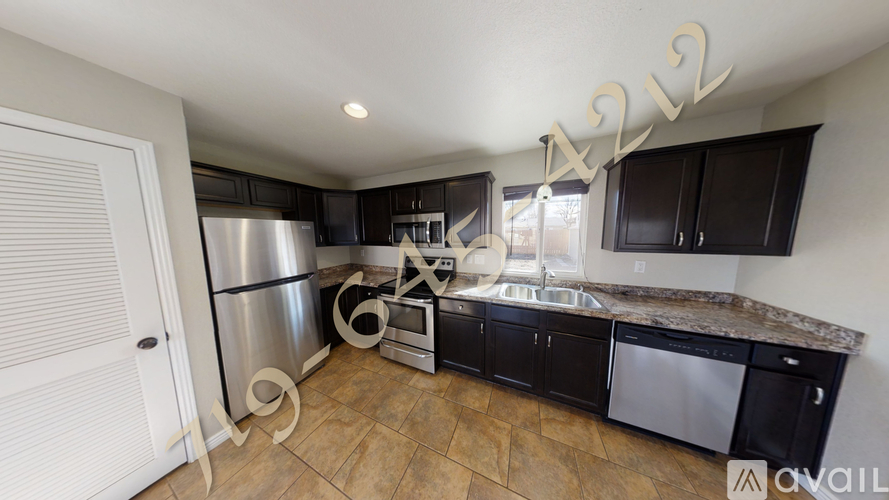 A kitchen with black cabinets and a stainless steel refrigerator.