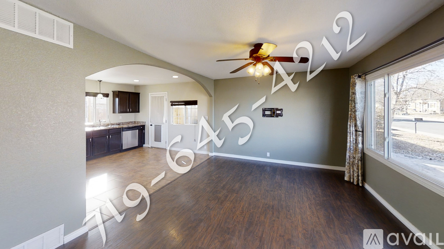 A spacious living room with a ceiling fan and hardwood floors.