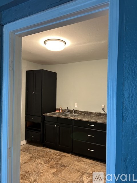 A kitchen with black cabinets and a granite countertop.